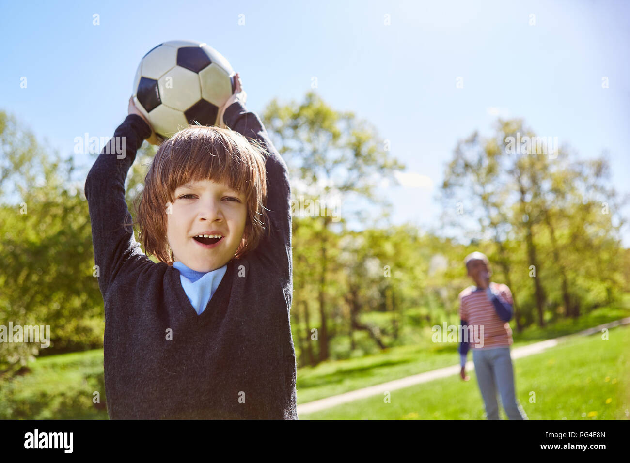 Boy plays football with friends on a meadow in summer and makes a throw-in Stock Photo