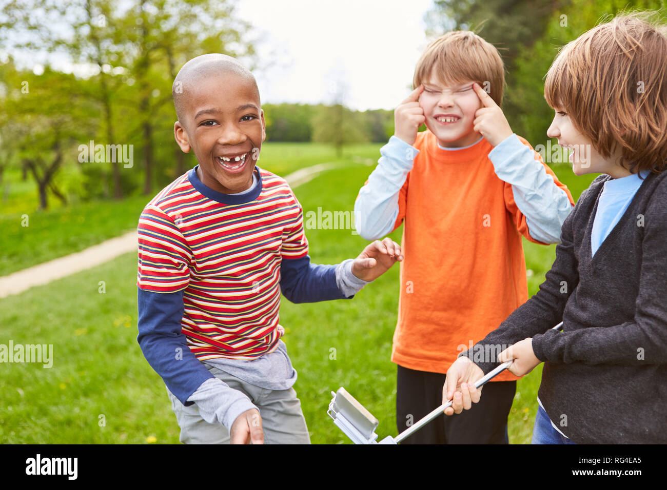 Three laughing kids as friends have fun together and make faces Stock Photo