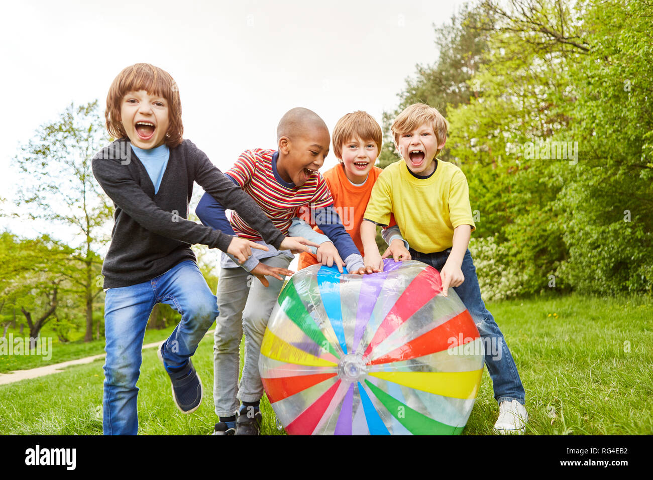 Kids have fun and laugh together while playing with a colorful big ball Stock Photo