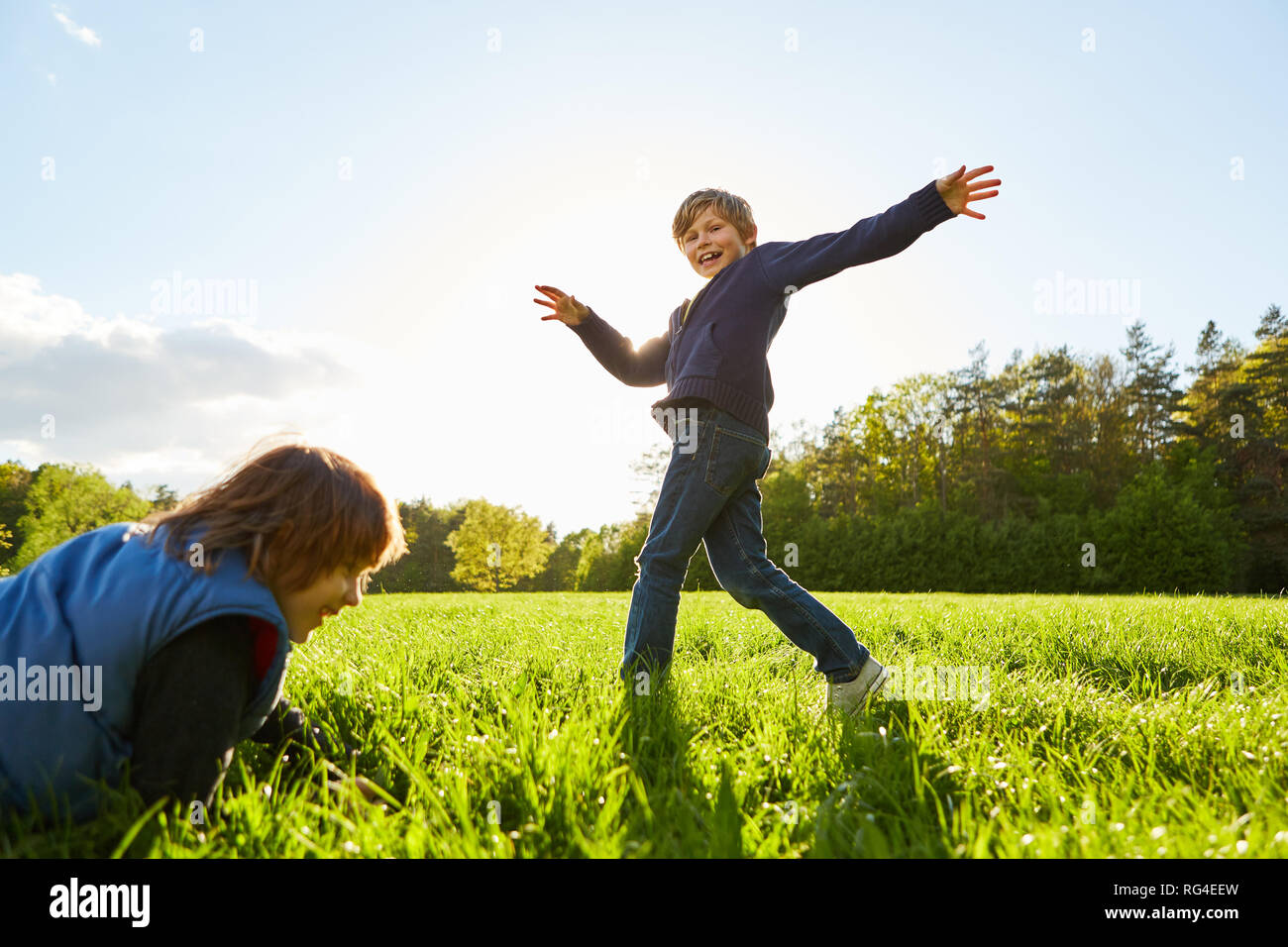 Boy is kidding around while dancing with a girl on a meadow in the sunshine Stock Photo