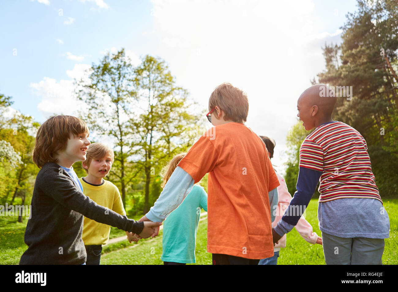 Children hold hands and dance in circles in summer in the park Stock