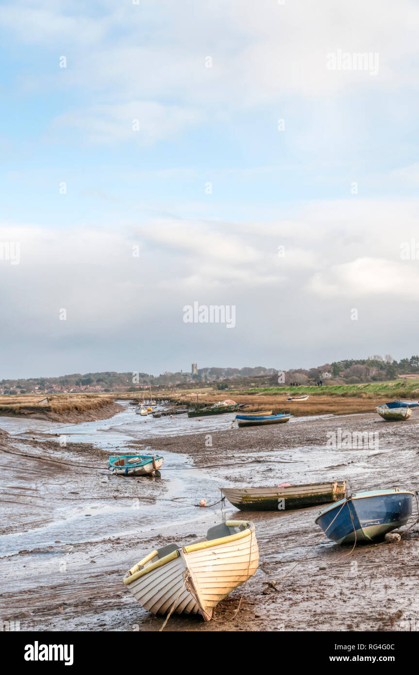 Boats at low tide moored in a creek through the salt marshes at Morston on the North Norfolk coast. Stock Photo