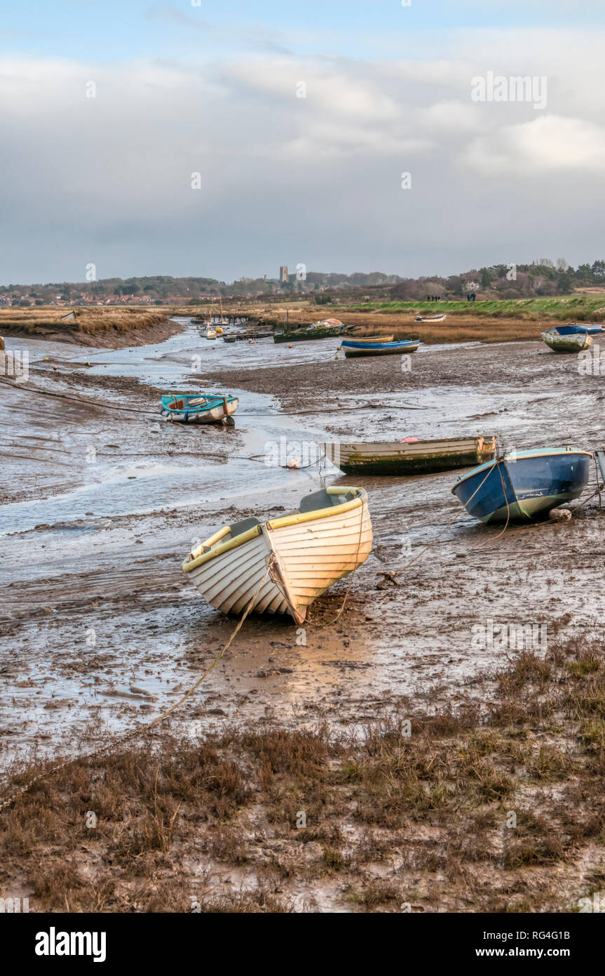 Boats at low tide moored in a creek through the salt marshes at Morston on the North Norfolk coast. Stock Photo