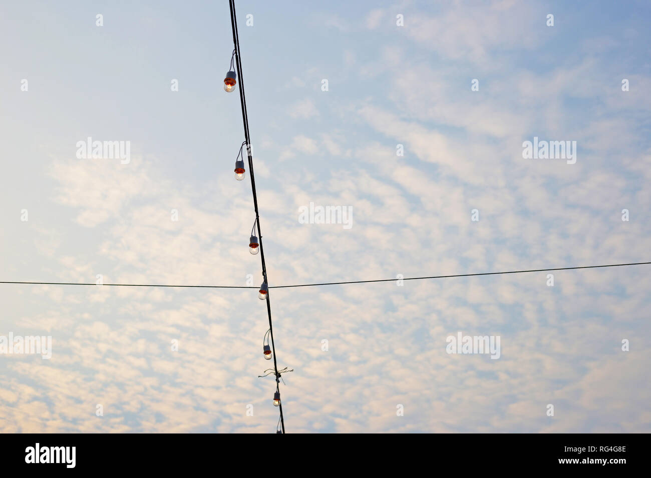 Light bulbs on string wire with blue sky Stock Photo