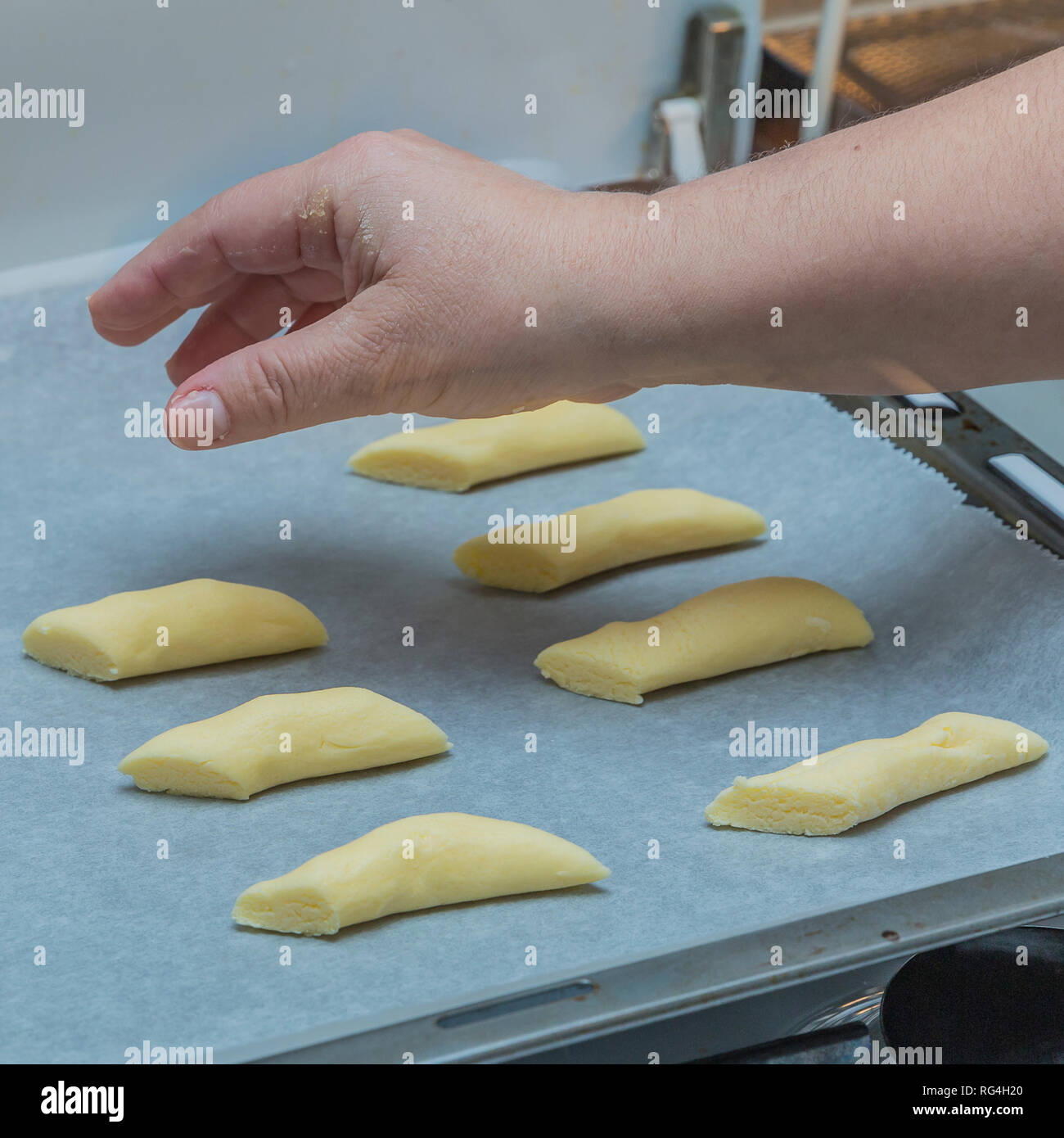 image of a hand of a woman placing raw cookies on a waxed paper in a