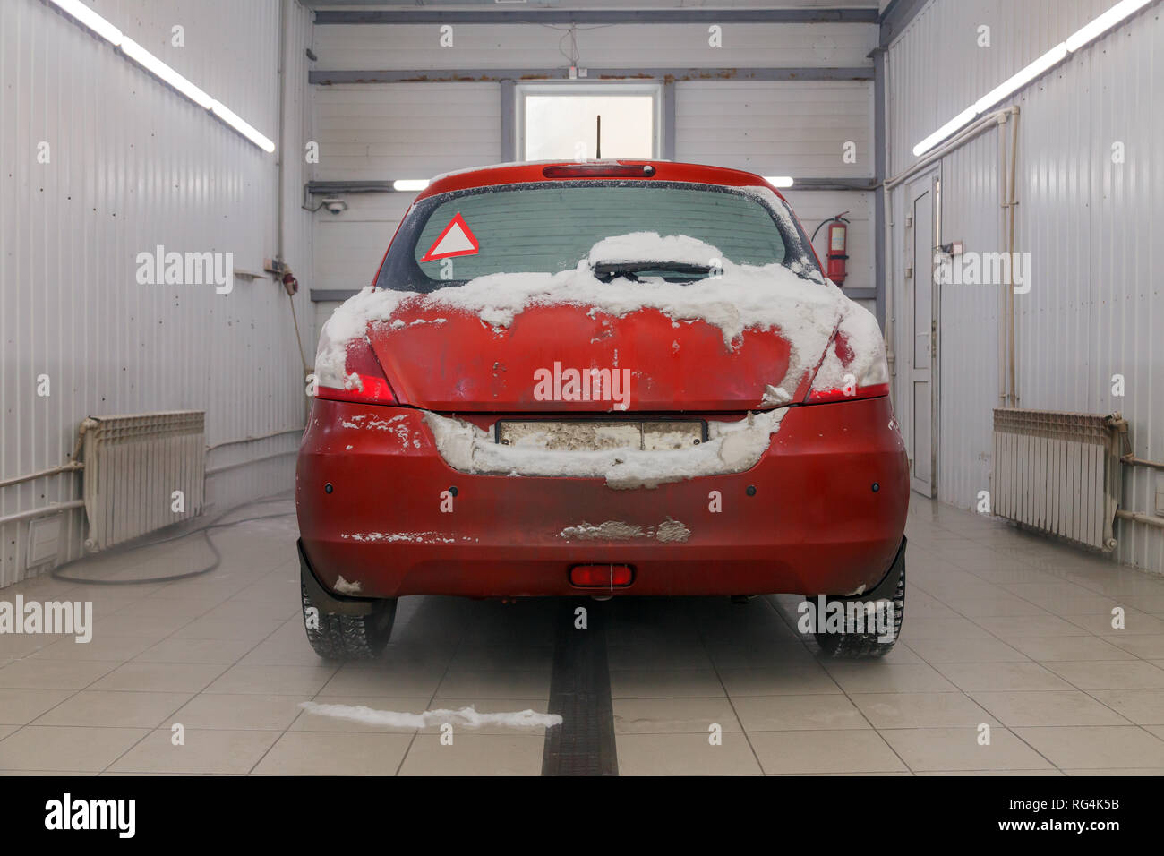 Russia Kemerovo 2019-01-05 Back of Suzuki Swift bright red small car in dirt snow on professional car wash. Concept comprehensive care for exterior, i Stock Photo