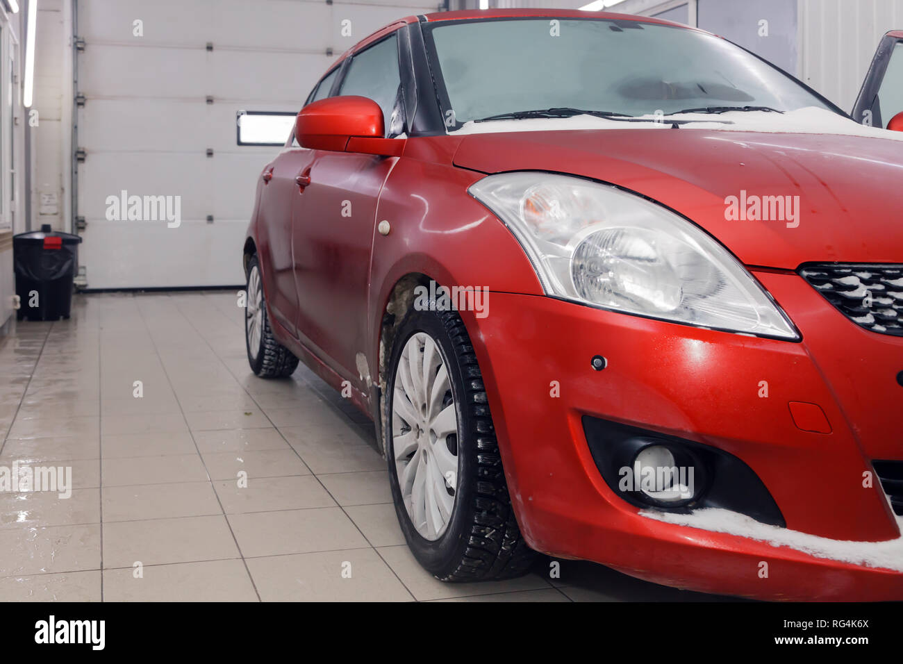 Russia Kemerovo 2019-01-05 Front Suzuki Swift bright red small car in dirt snow on professional car wash. Concept comprehensive care for exterior, int Stock Photo