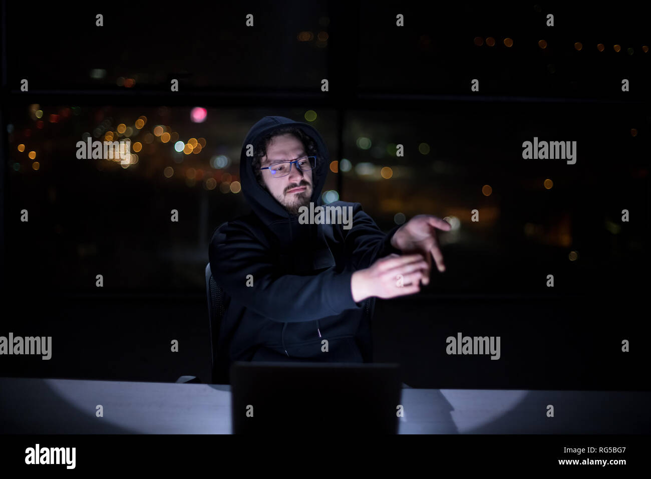 Young talented hacker using laptop computer while working in dark ...