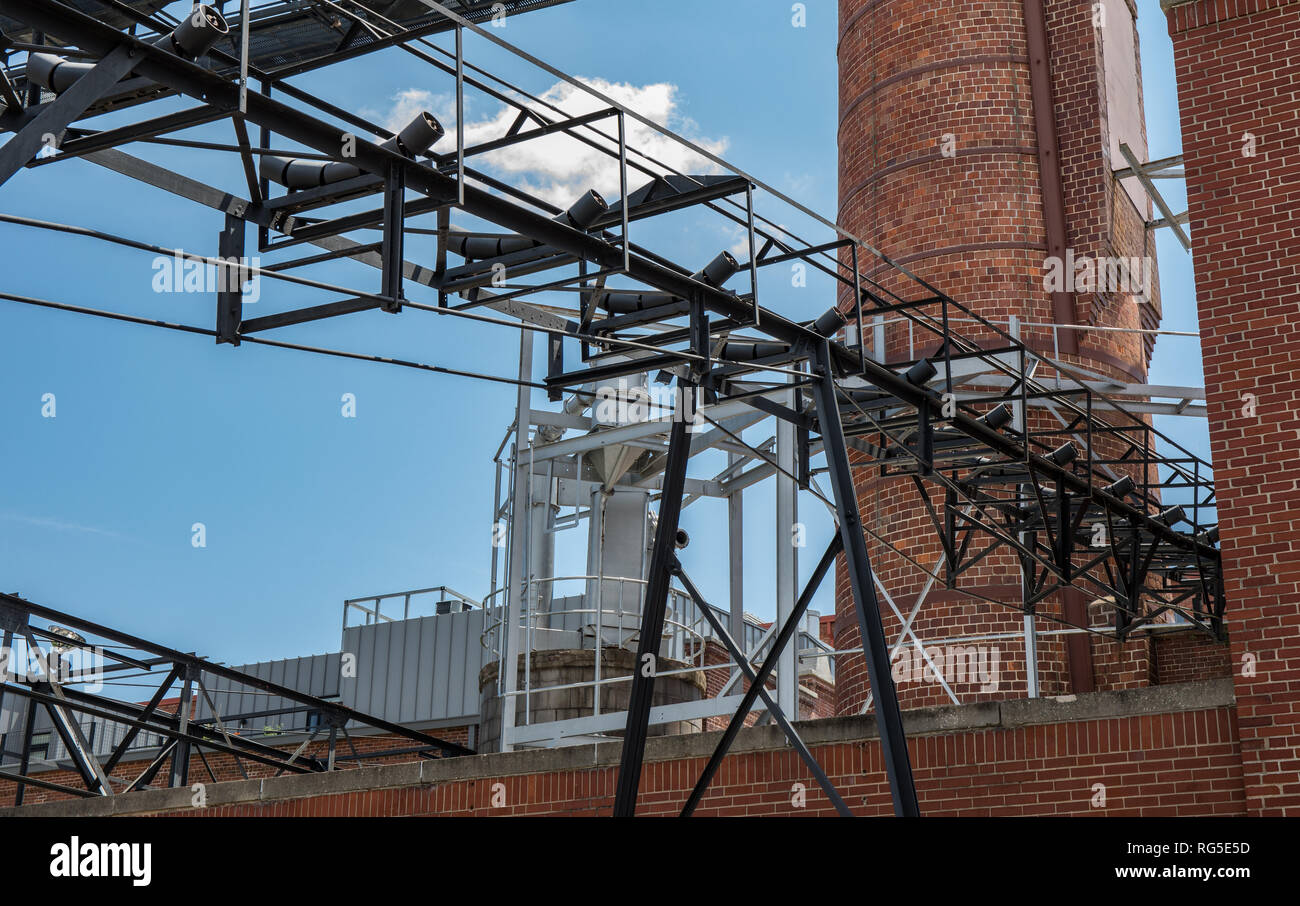 An industrial looking complex with a conveyor belt and smoke tower. Stock Photo