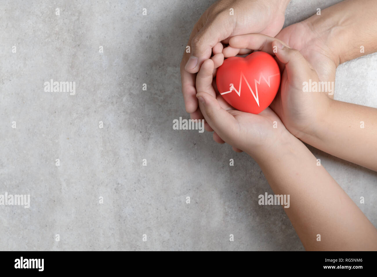Father and child hands holding red heart on marble background, health ...