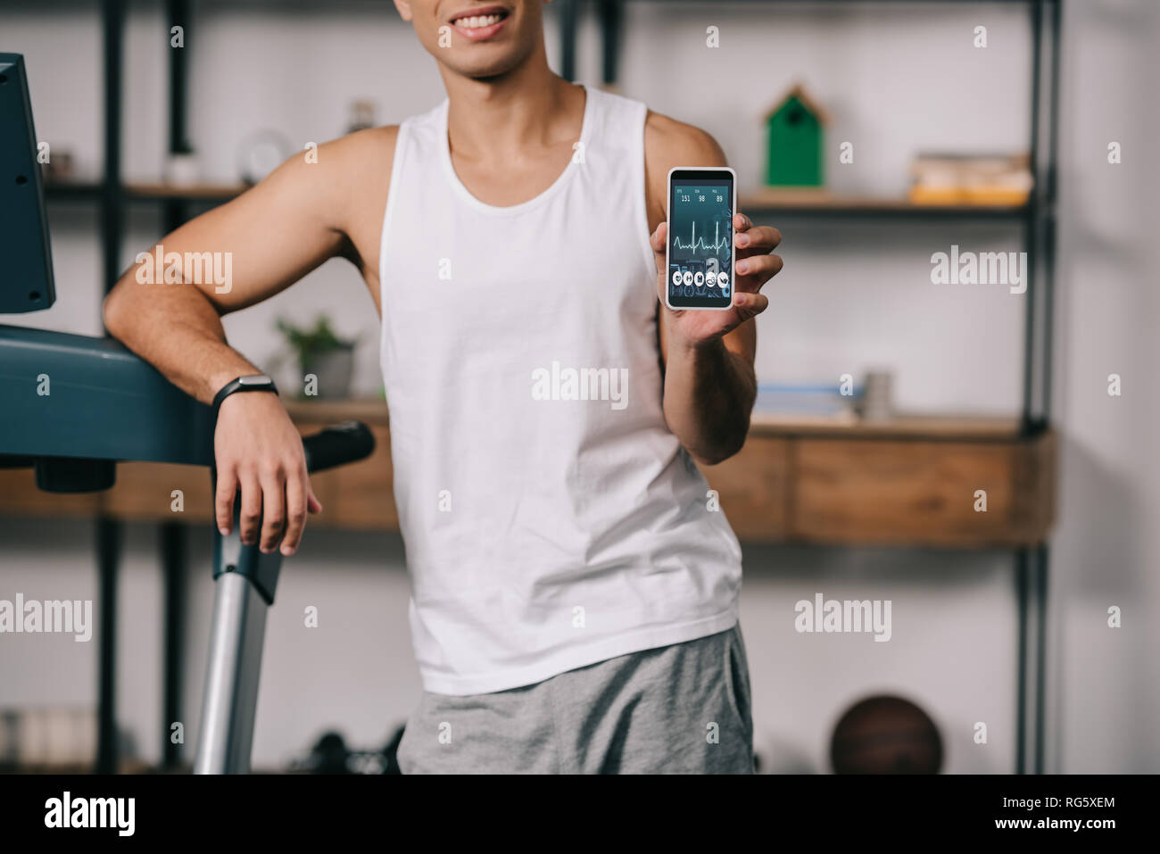 cropped view of bi-racial man holding smartphone with  hearbeat rate on screen Stock Photo