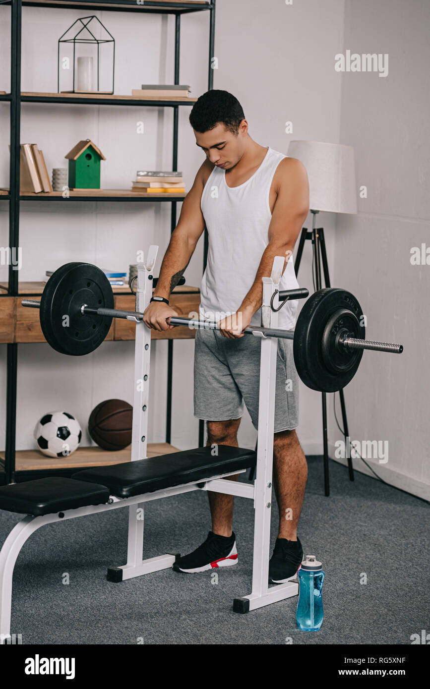 handsome bi-racial man workout with barbell in home gym Stock Photo - Alamy