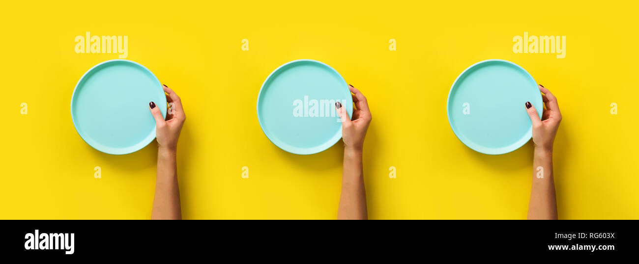 Pattern of female hands holding empty blue plate on yellow background with copy space. Healthy eating, dieting concept. Banner. Stock Photo