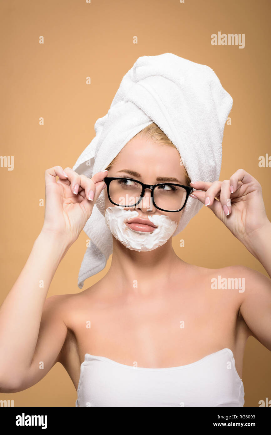 beautiful girl with towel on head and shaving cream on face adjusting