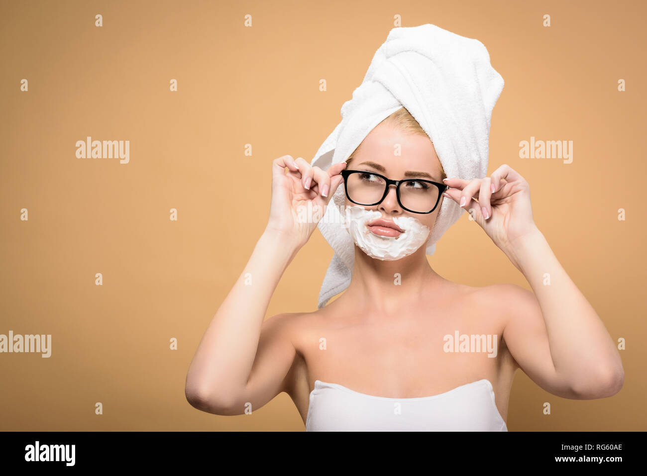 young woman with towel on head and shaving cream on face adjusting