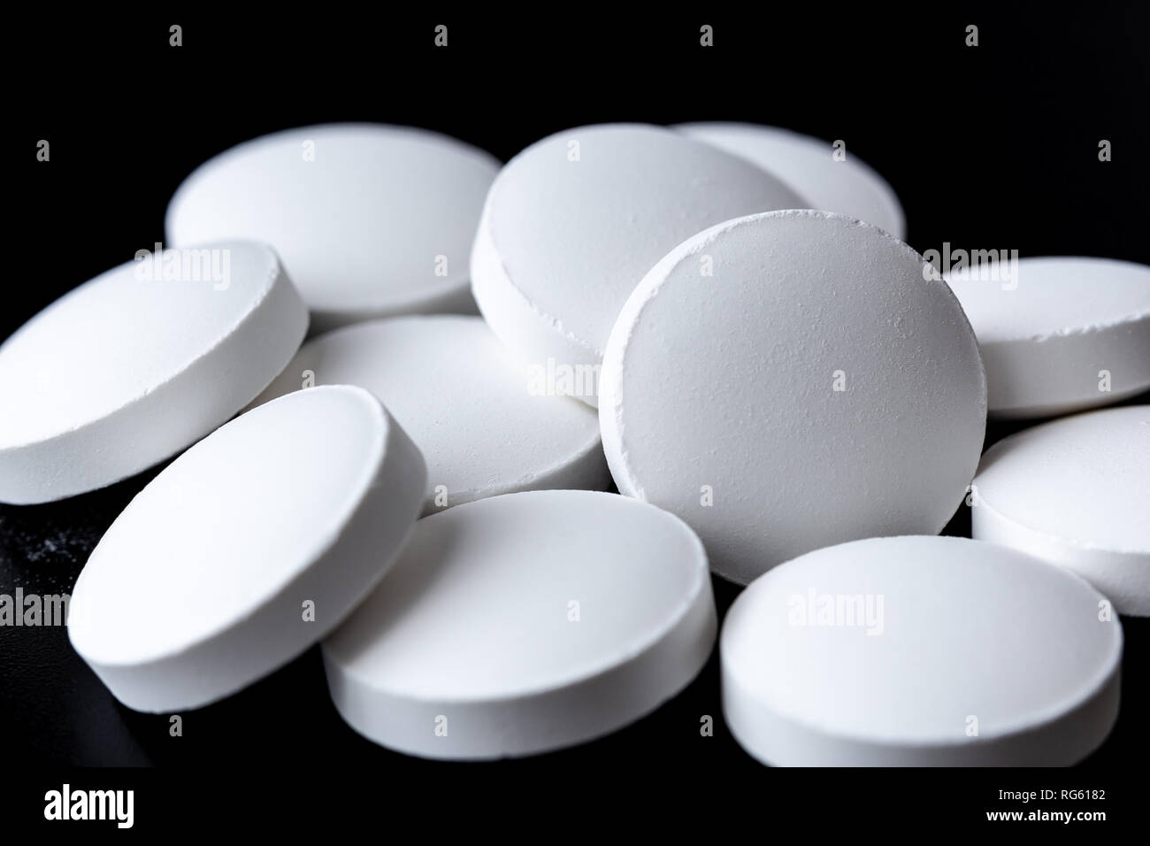 Heap of white pills on black background close up Stock Photo