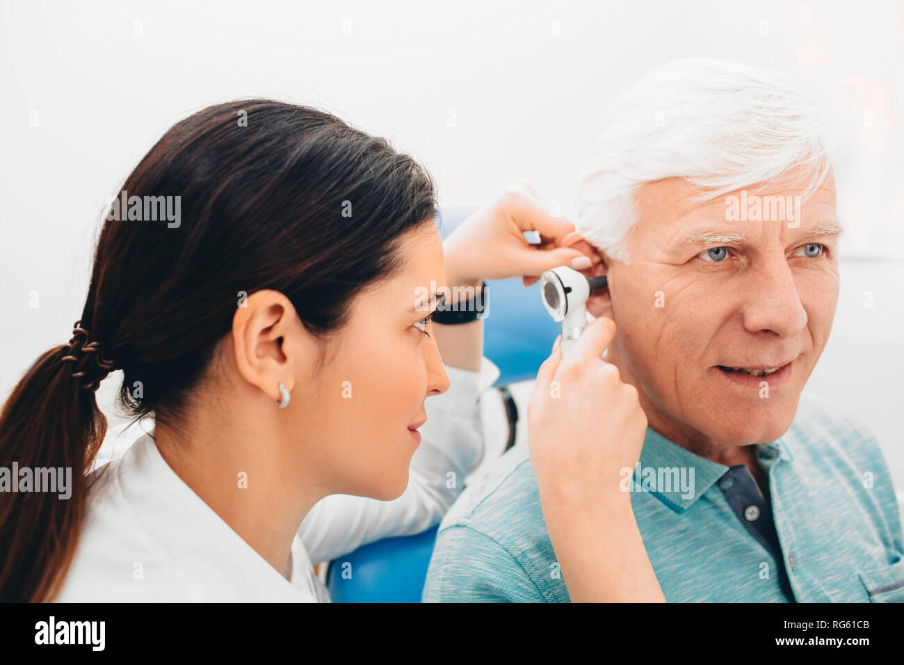 doctor examining elderly patient ear , using otoscope, in doctors office. Senior man getting medical ear exam at clinic. Stock Photo