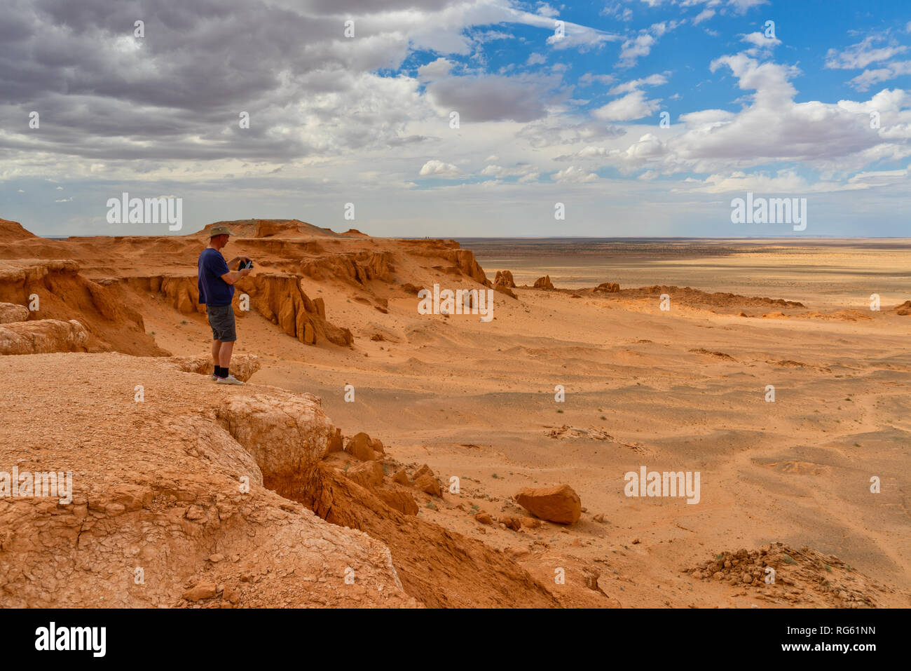 Man standing in desert taking a photo, Flaming Cliffs, Gobi Desert, Bulgan, Mongolia Stock Photo