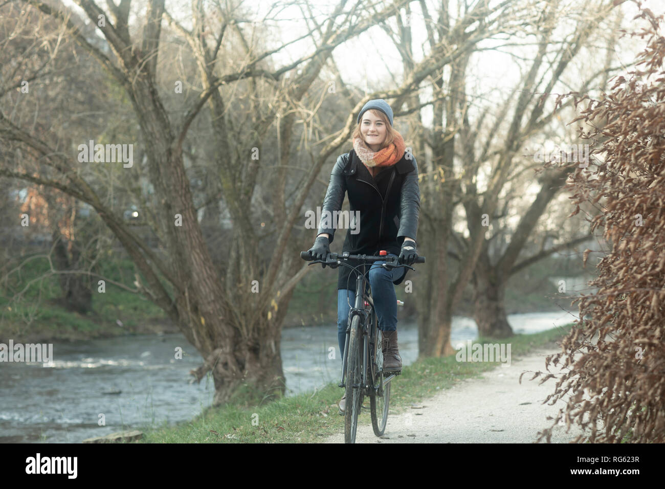 Woman cycling along a footpath by the river, Germany Stock Photo