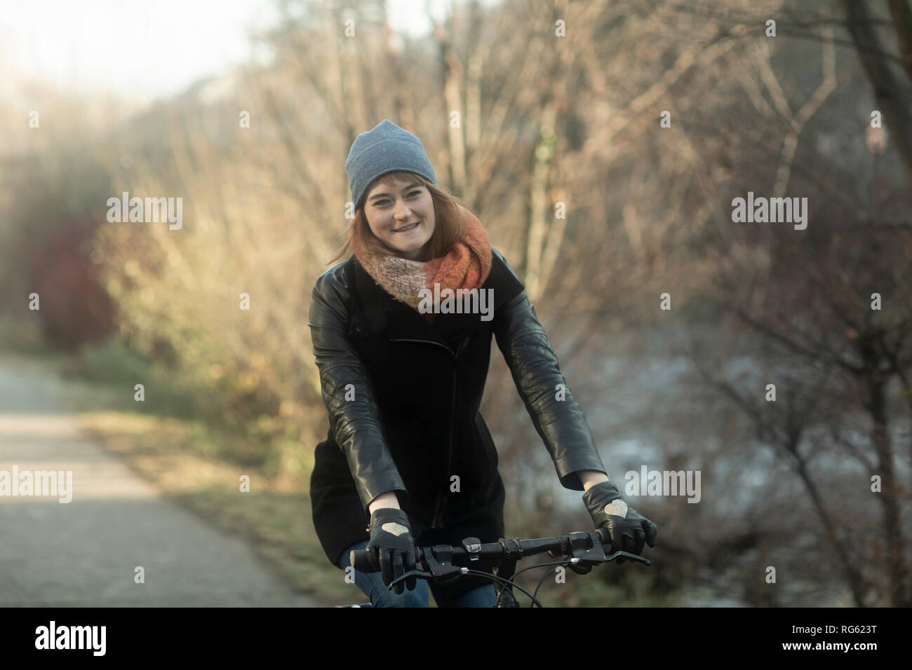 Woman cycling along a footpath by the river, Germany Stock Photo