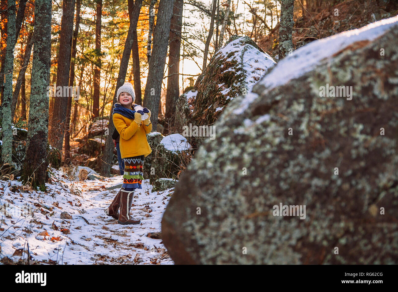 Smiling girl standing in forest holding a piece of frozen ice, United States Stock Photo