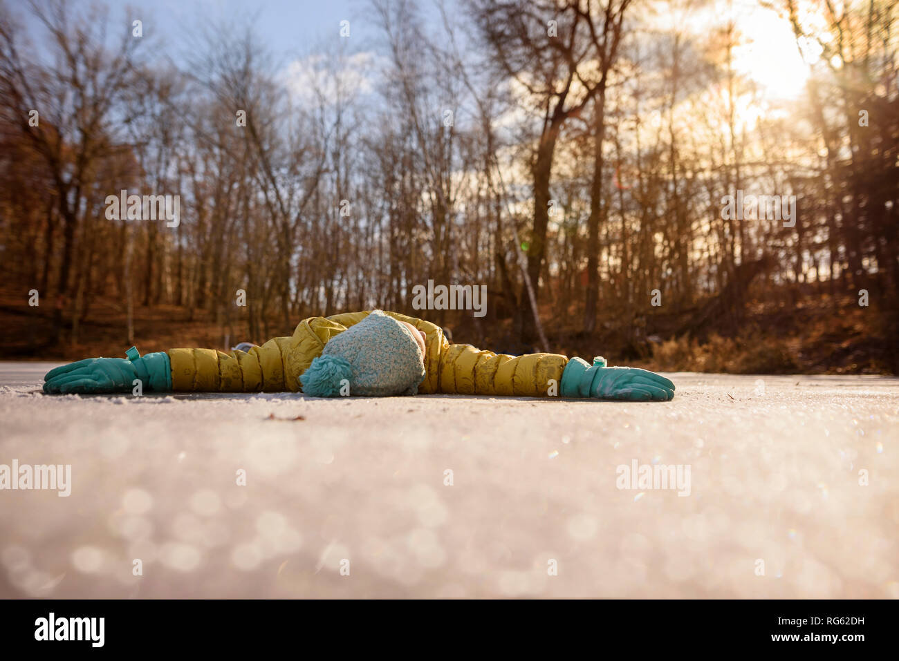 Girl lying on a frozen pond with her arms outstretched, United States Stock Photo