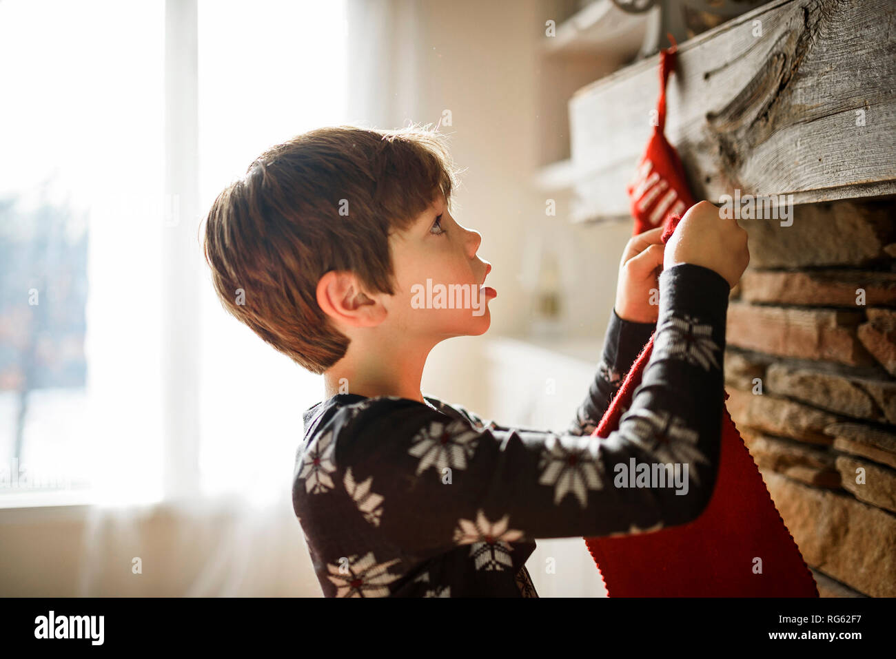 Boy hanging a Christmas stocking on a fireplace Stock Photo