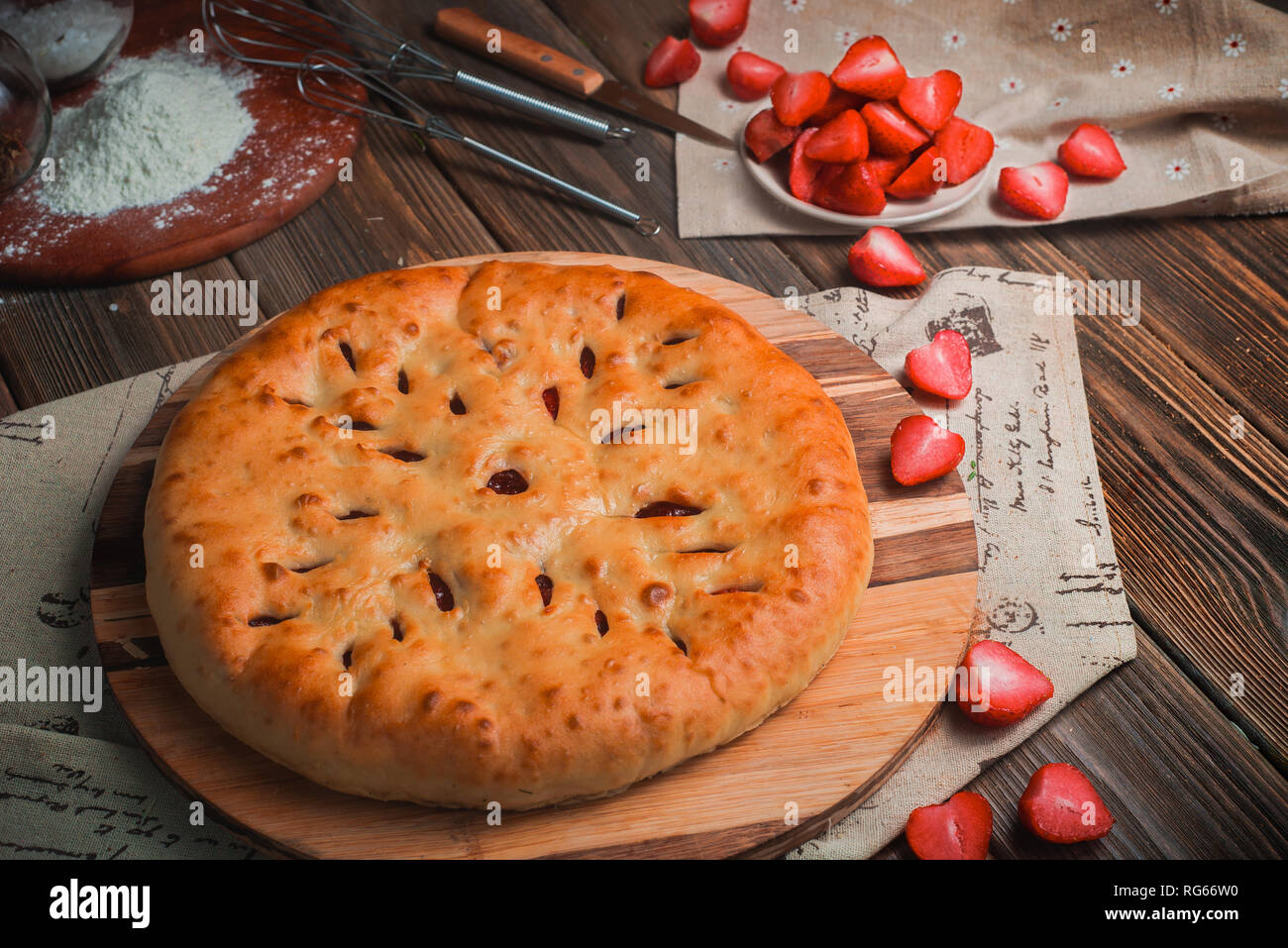 Homemade strawberry pie on a wooden kitchen table with ingredients. Traditional baking header. Delivery menu with copy space Stock Photo