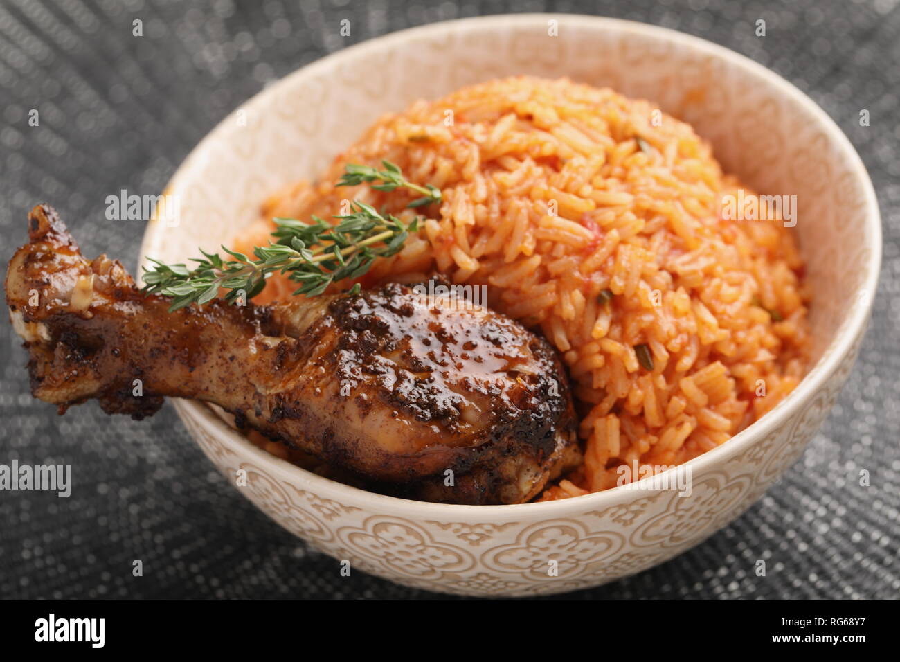 Nigerian Jollof Rice with roasted chicken thigh and thyme Stock Photo