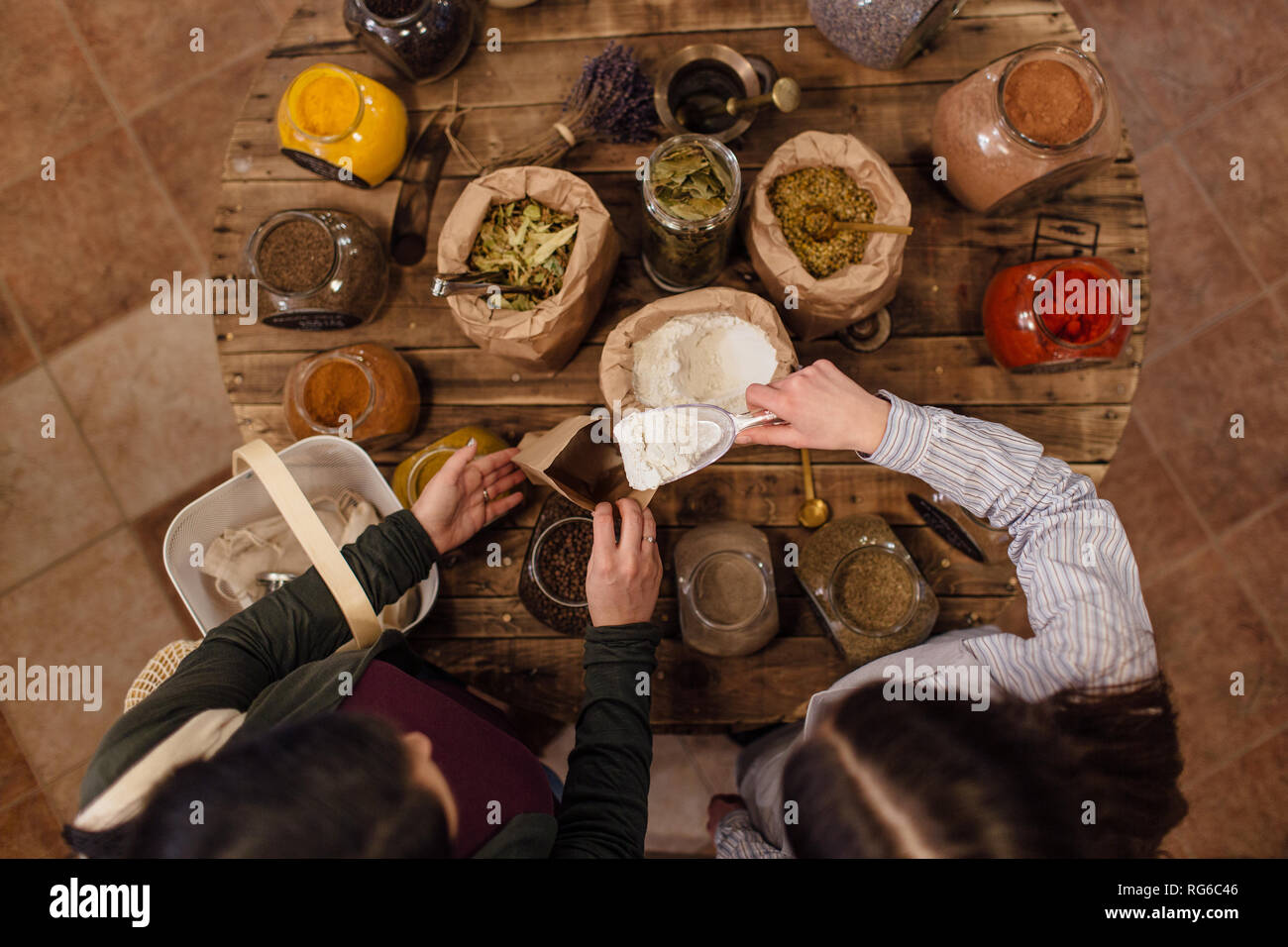 High angle view of shop assistant putting flour into paper bag for customer at zero waste shop. Top view. Stock Photo