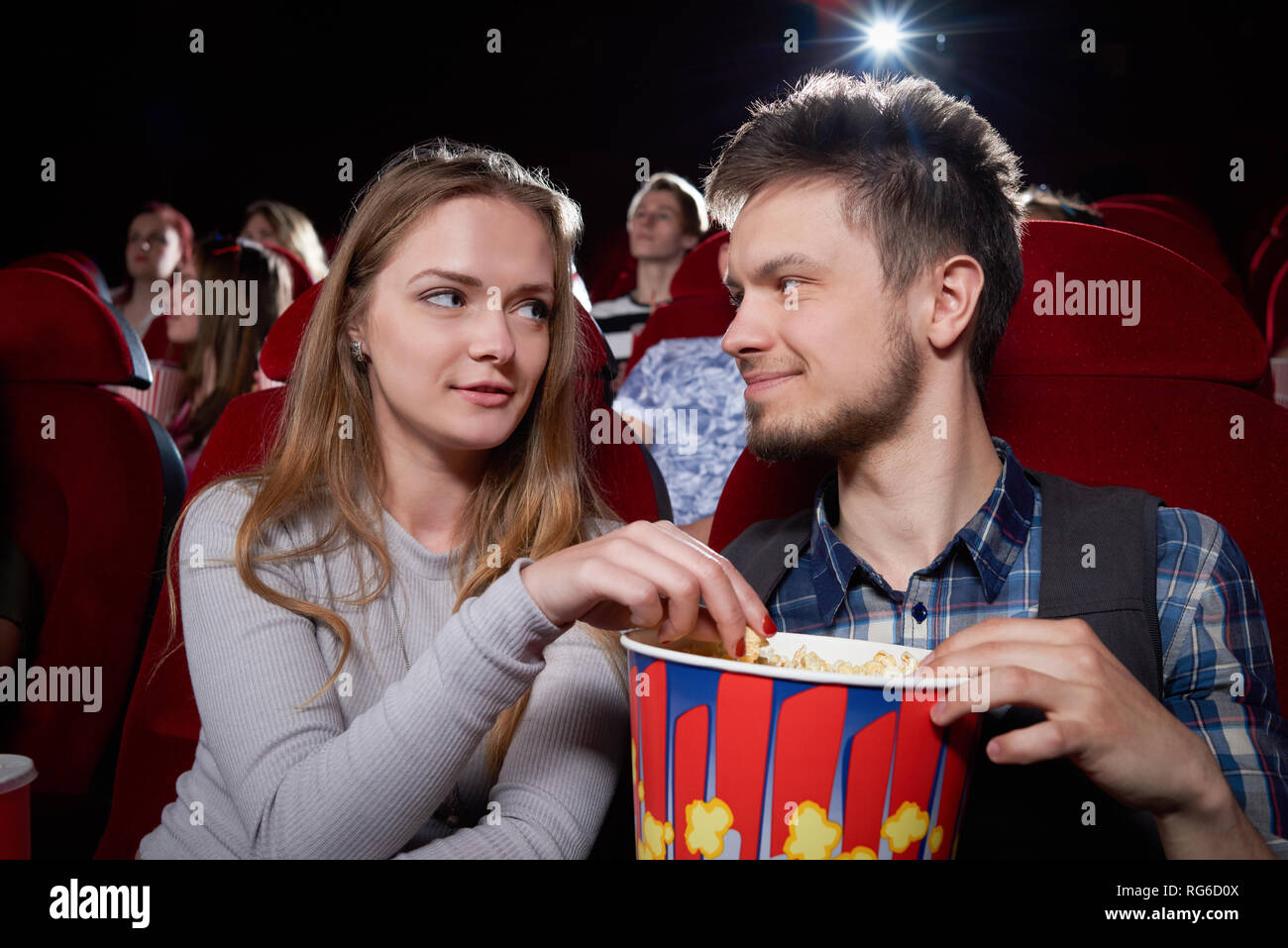 Front View Of Young Couple Eating Popcorn And Looking Each Other