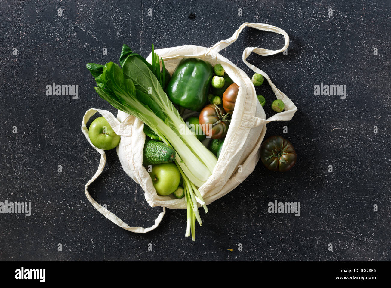 Fresh Organic Food Vegetables and Fruit In Fabric Eco Bag. Vegetarian Or Vegan Food On Dark Background Top View Flat Lay Stock Photo