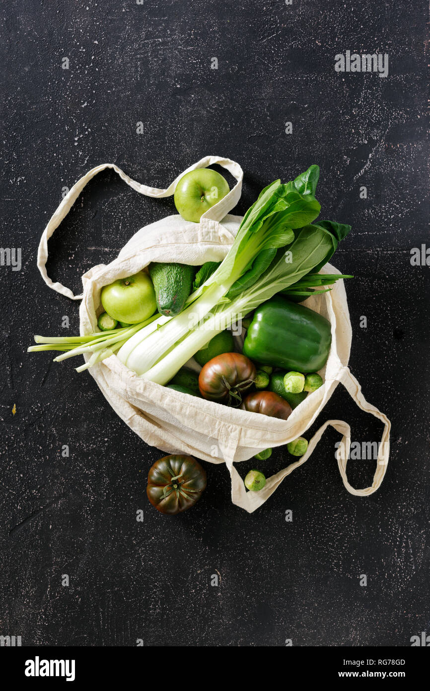 Fresh Organic Food Vegetables and Fruit In Fabric Eco Bag. Vegetarian Or Vegan Food On Dark Background Top View Flat Lay Stock Photo