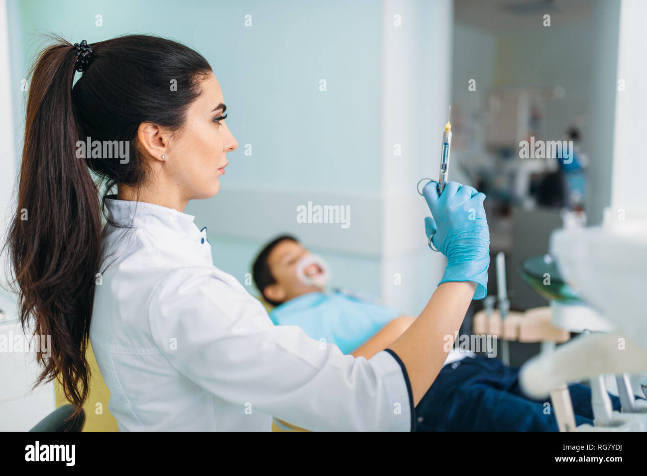 Female dentist with syringe of anesthesia, boy in dental chair