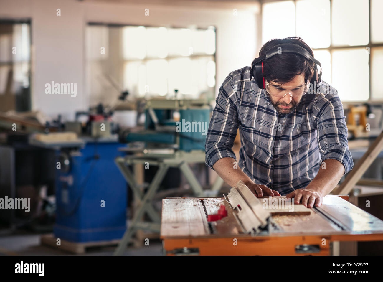 Woodworker using a table saw in his workshop Stock Photo