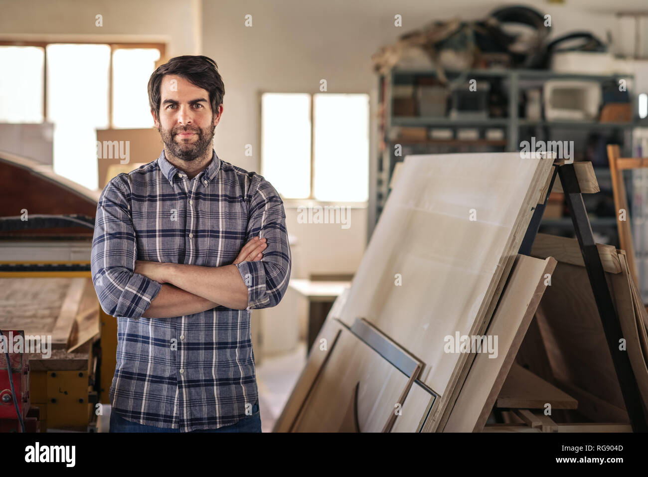 Woodworker standing with his arms crossed in a workshop Stock Photo
