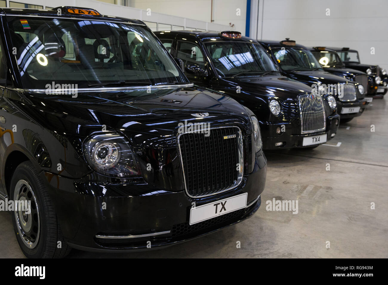 The new London EV taxi ahead of a row of all the cars ever manufactured by the London EV Company (formerly the London Taxi Company) at the R&D Centre and Manufacturing Plant, Ansty Park, Coventry. Stock Photo
