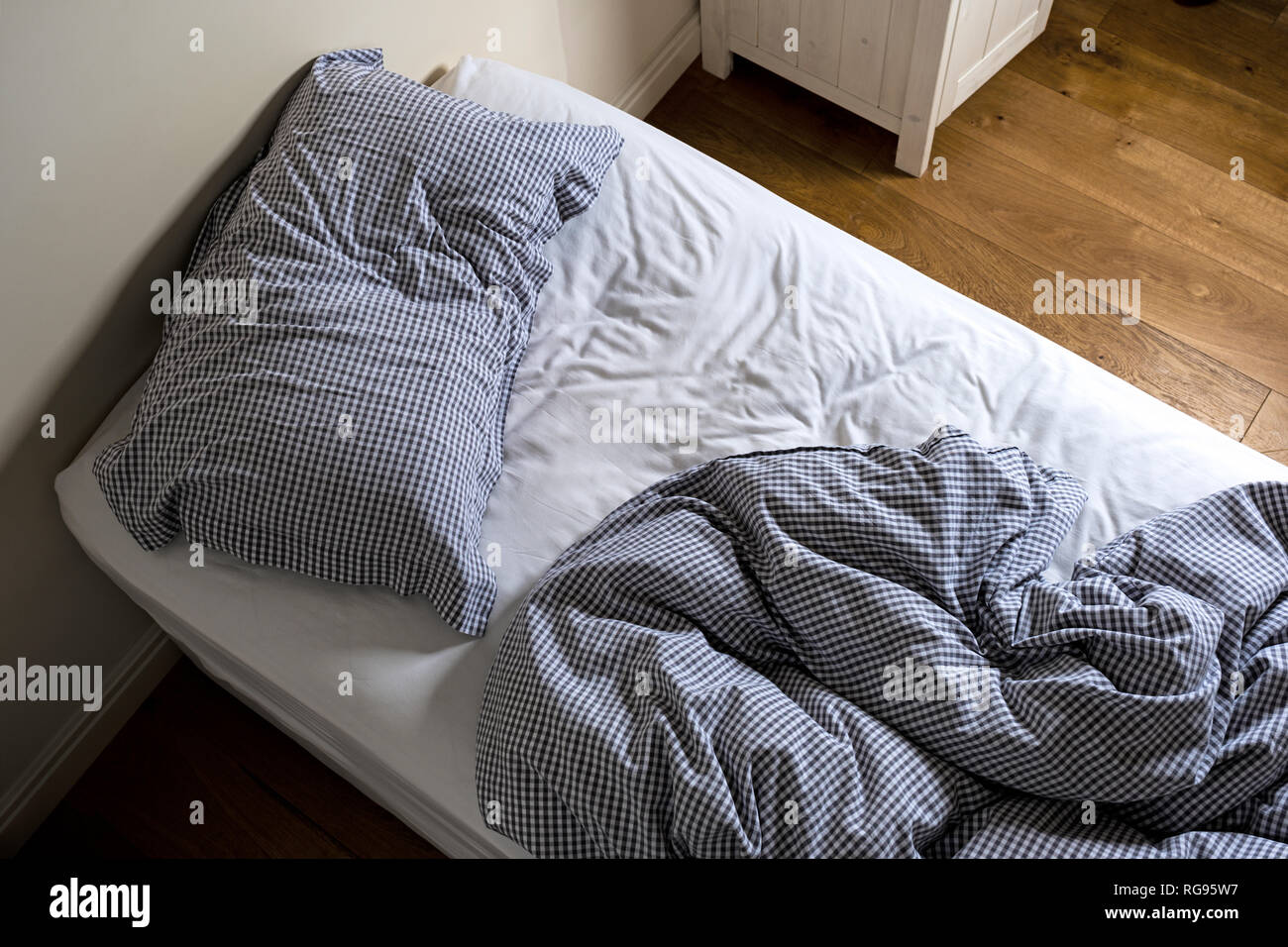 An unmade single bed. Stock Photo