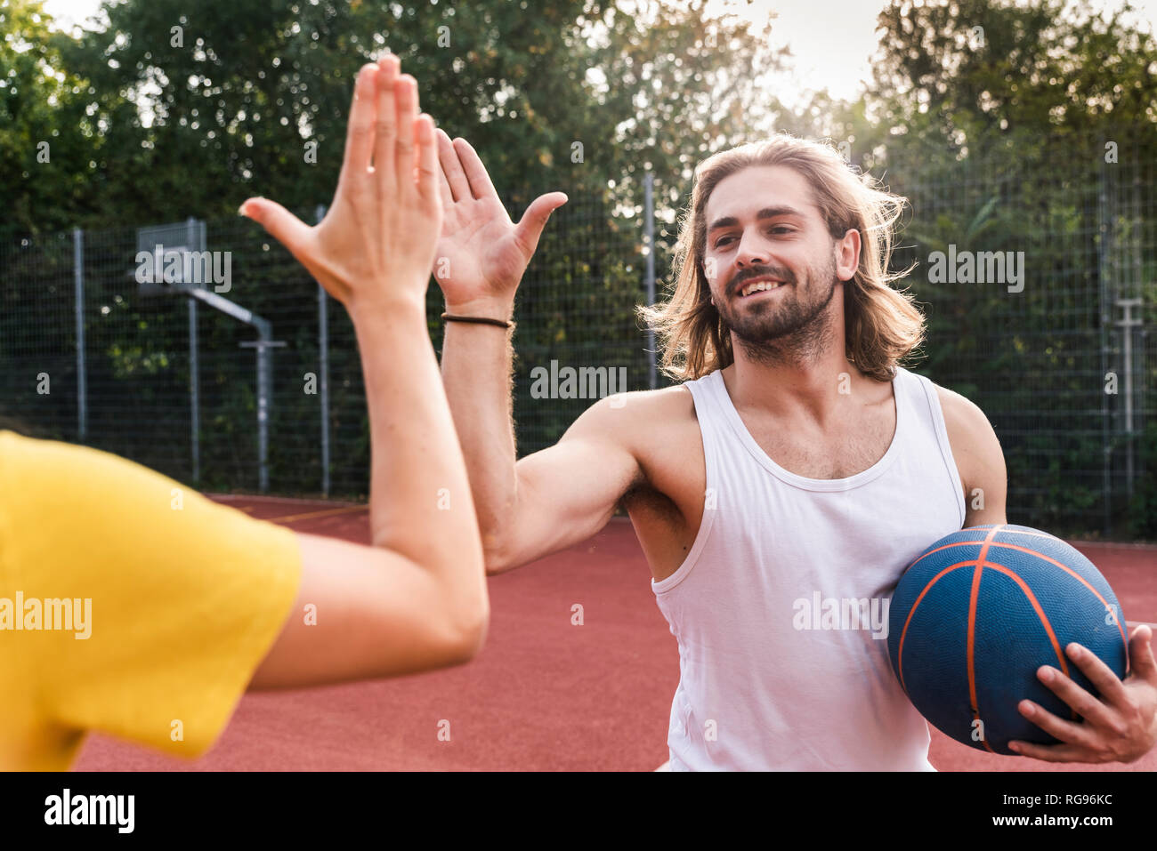 Young man and young woman highfiving after basketball game Stock Photo