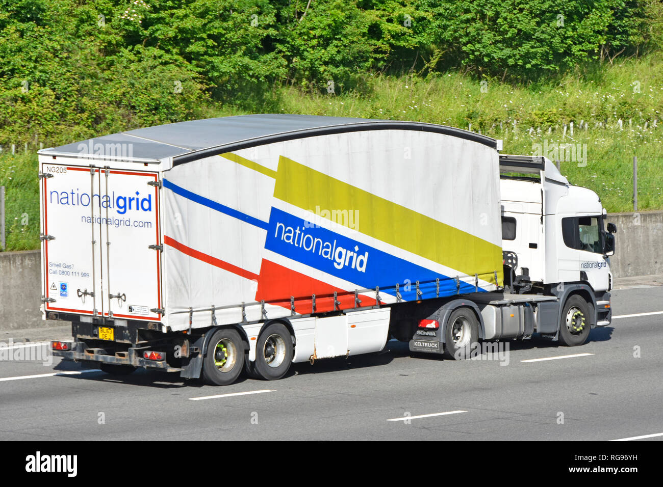 Side & back view of National Grid hgv lorry truck & colourful graphics on side of aerodynamics shaped articulated trailer on motorway Essex England UK Stock Photo