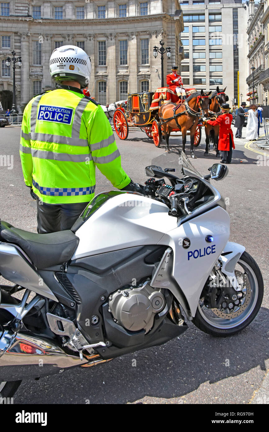 UK motorbike & metropolitan police officer blocking road at Admiralty Arch while horse drawn State Landau carriage completes formalities London UK Stock Photo