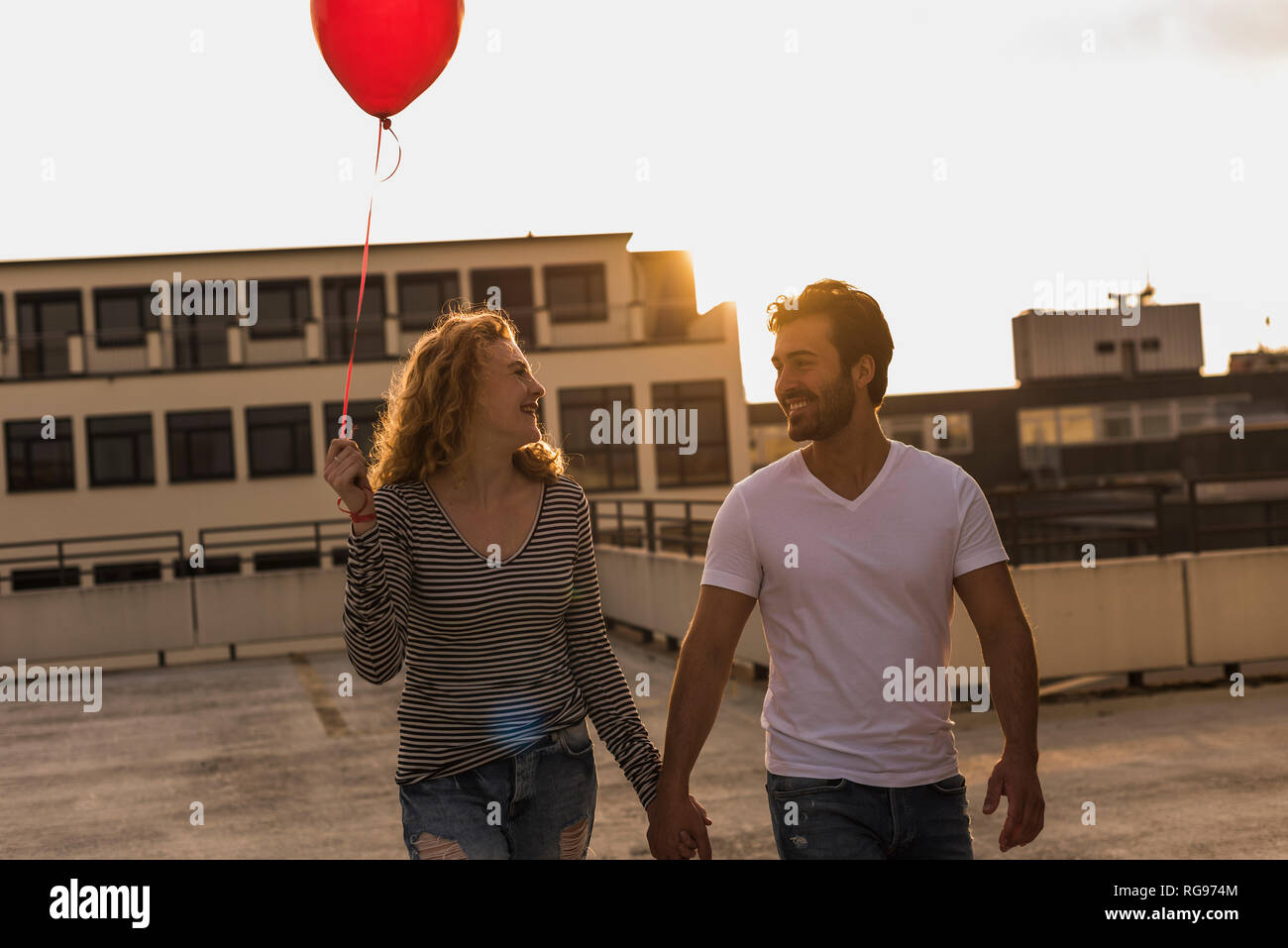 Happy young couple on roof terrace at sunset Stock Photo
