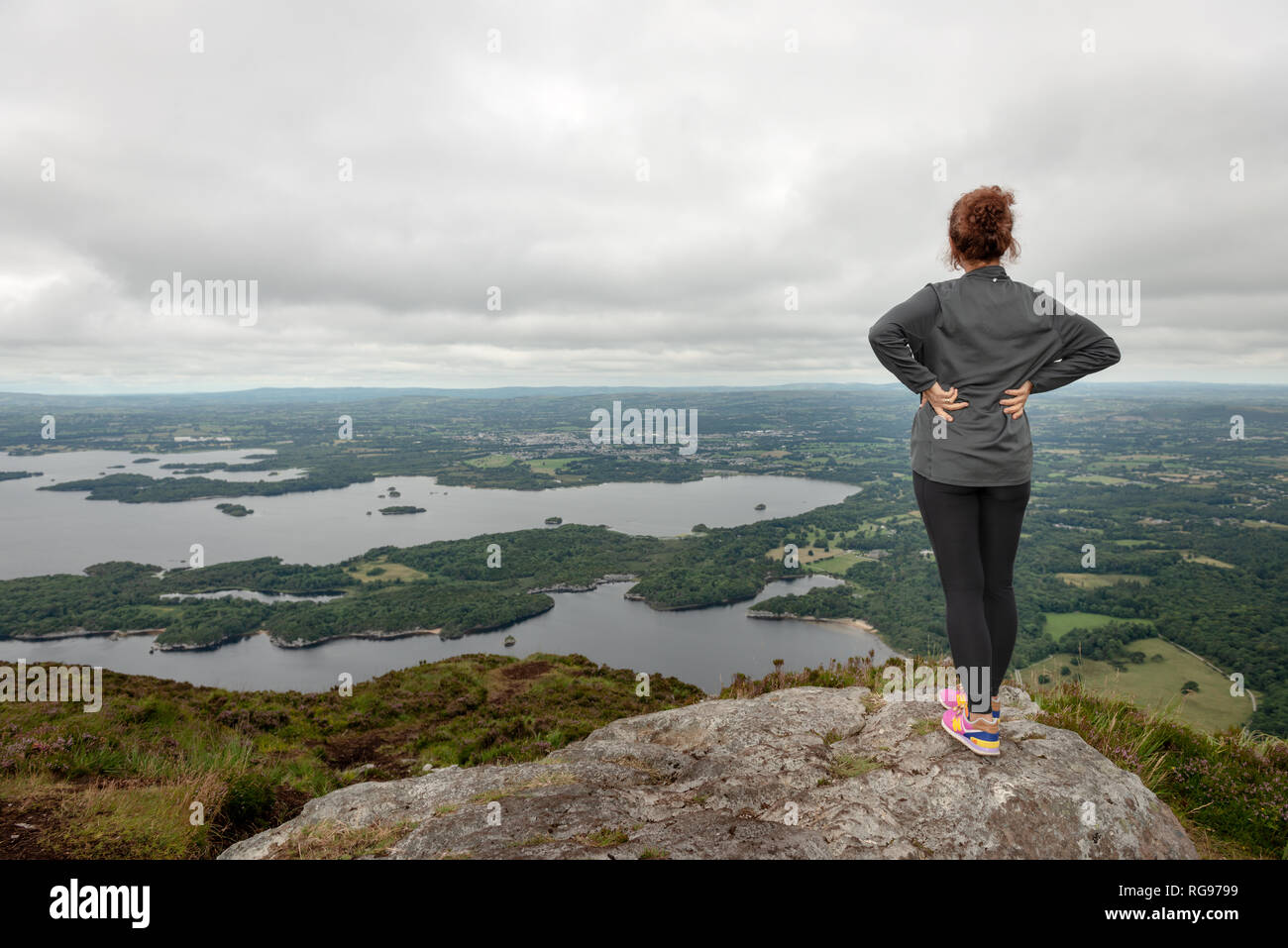 Landscape view to the Lakes of Killarney and Killarney Valley from Torc Mountain summit and a female hiker in Killarney National Park, Ireland Stock Photo