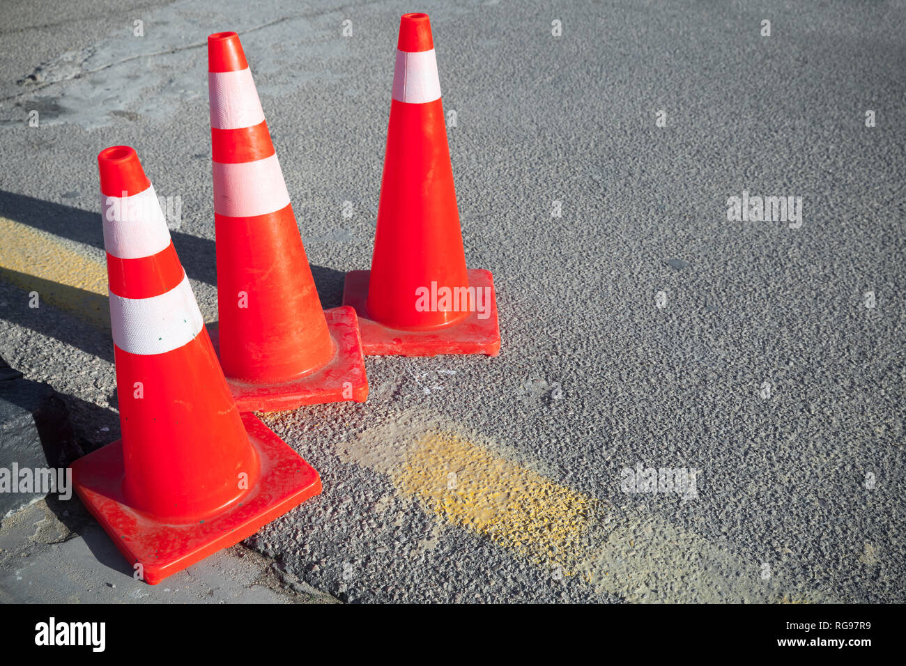 Red striped warning road cones stand on a roadside Stock Photo