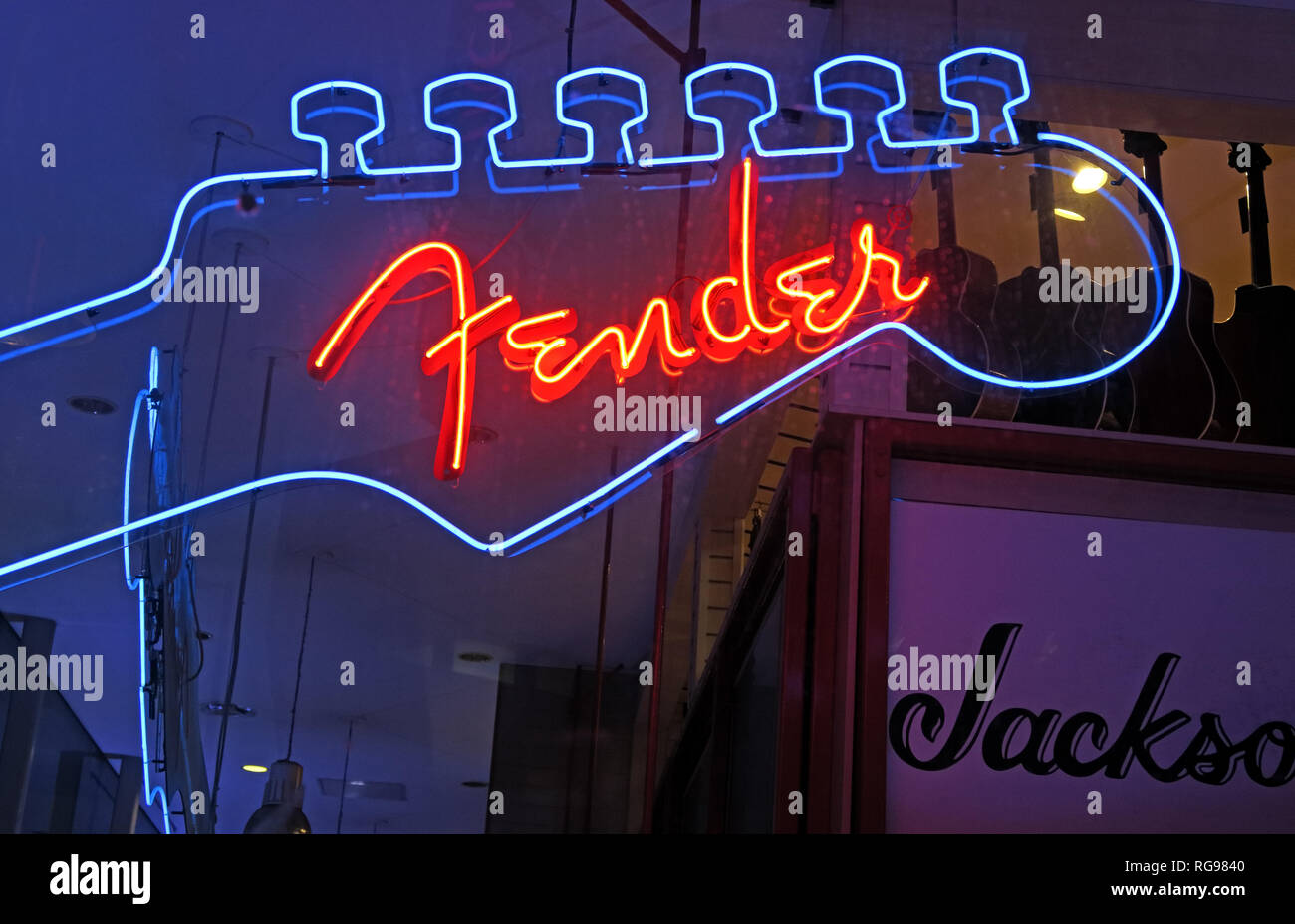 Neon Fender guitar logo glowing in a specialist musical instrument shop, combining iconic electric-guitar branding with traditional music retail. Stock Photo