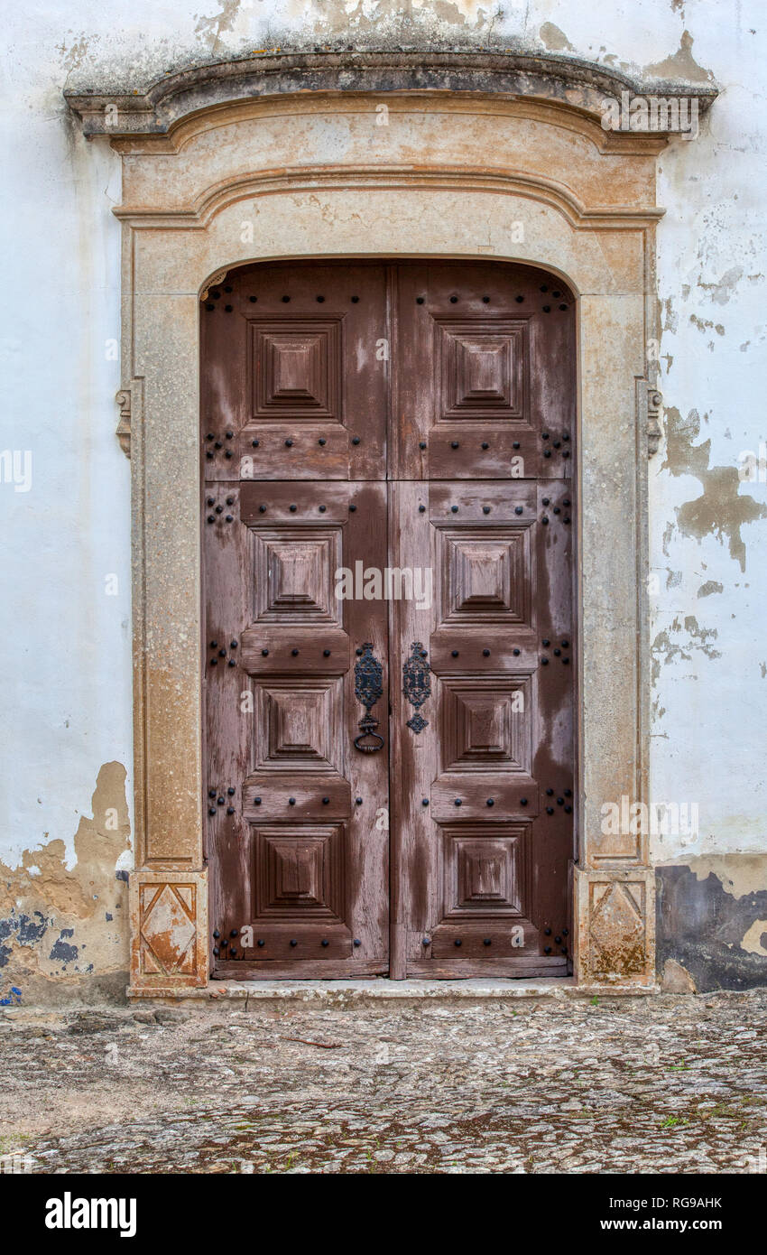 Photograph taken of a wood, brown, weathered church door in the medieval village of Obidos, Portugal. Stock Photo