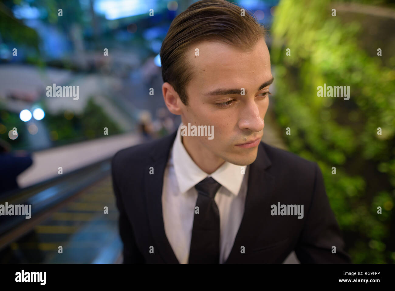 Young businessman standing at escalator while thinking Stock Photo