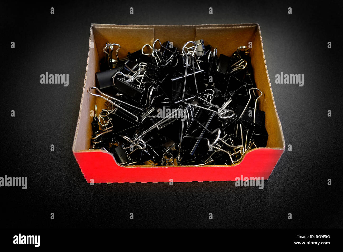 Box of binder clips binderclips office supplies of paperclips on desk Stock Photo