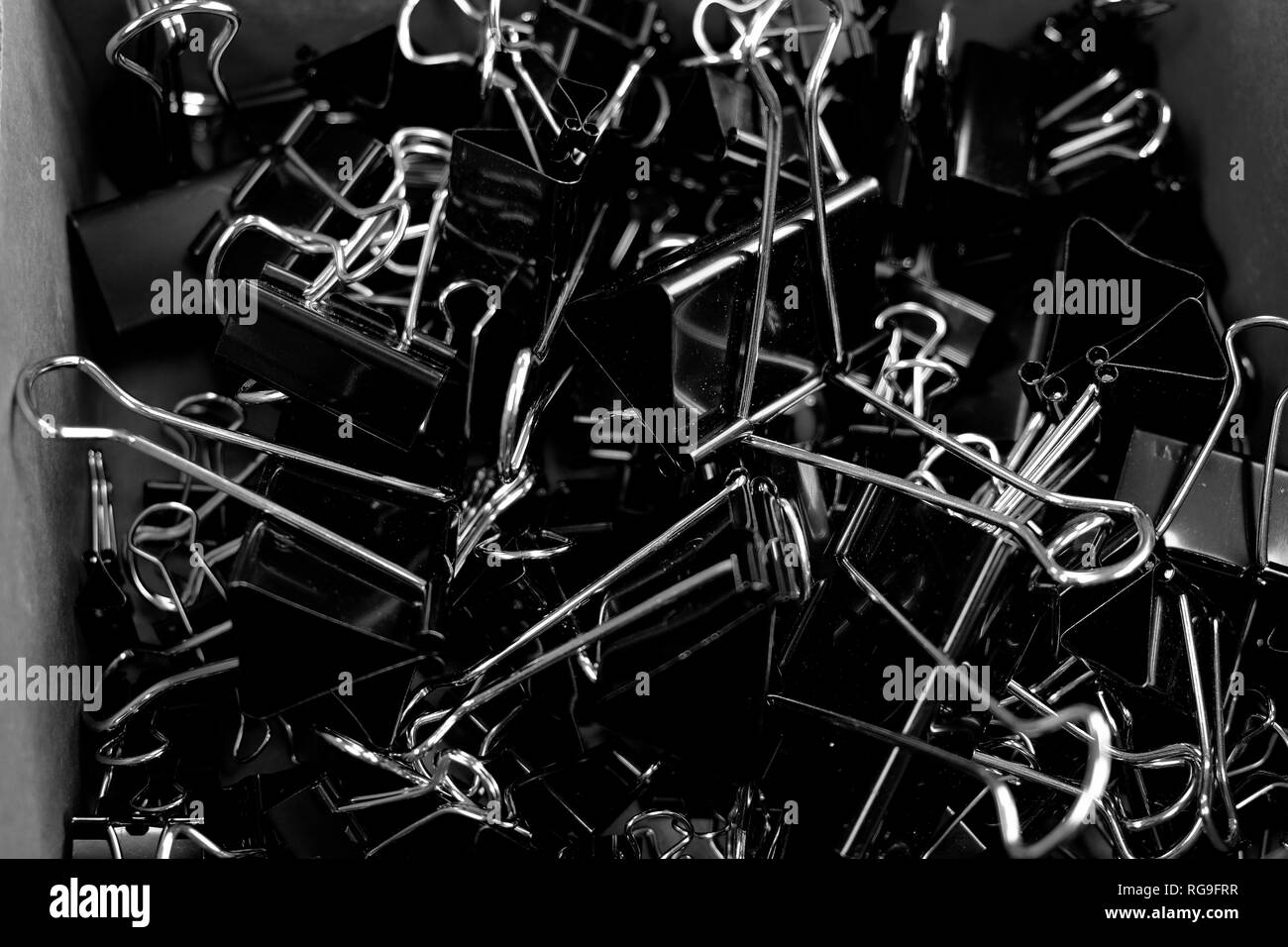 Box of binder clips binderclips office supplies of paperclips on desk Stock Photo