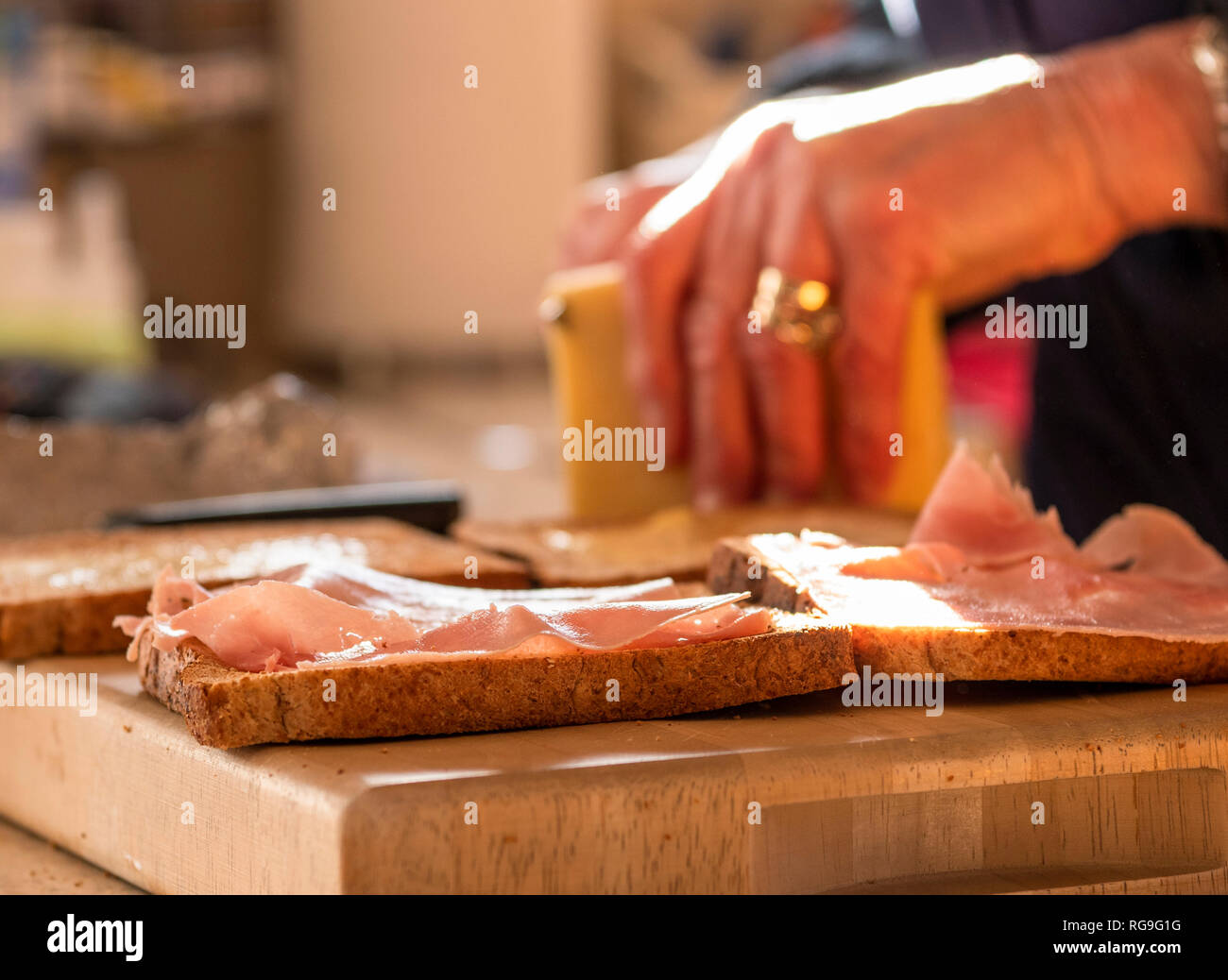 Woman cutting cheese in the background while making sandwiches Stock Photo